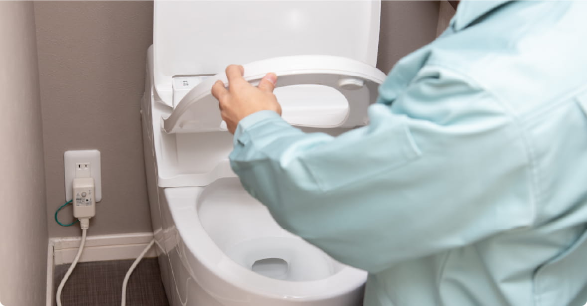 作業服の人がトイレを修理している様子