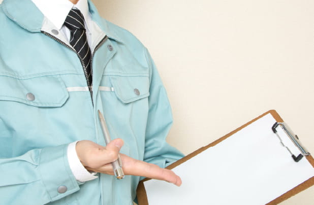 作業服の人が資料とペンを持って説明している様子