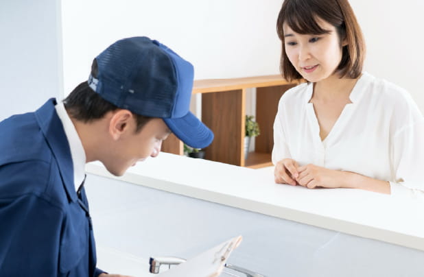 水道業者の人が作業着で対応し、それを見守る女性の様子